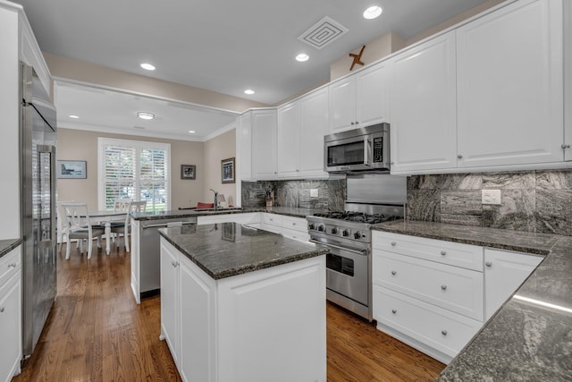 kitchen with visible vents, premium appliances, a peninsula, dark wood finished floors, and crown molding
