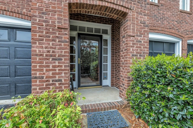 entrance to property with a garage and brick siding