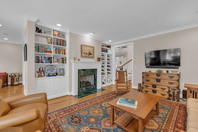 living area with wood finished floors, ornamental molding, stairway, and built in features