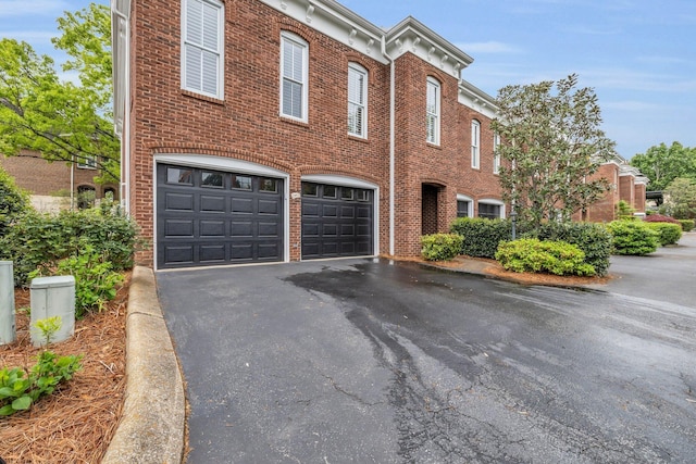 view of front of property featuring brick siding, driveway, and an attached garage