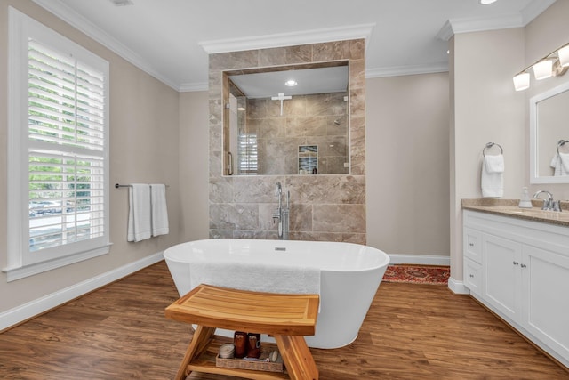 bathroom featuring a freestanding tub, baseboards, crown molding, a tile shower, and wood finished floors