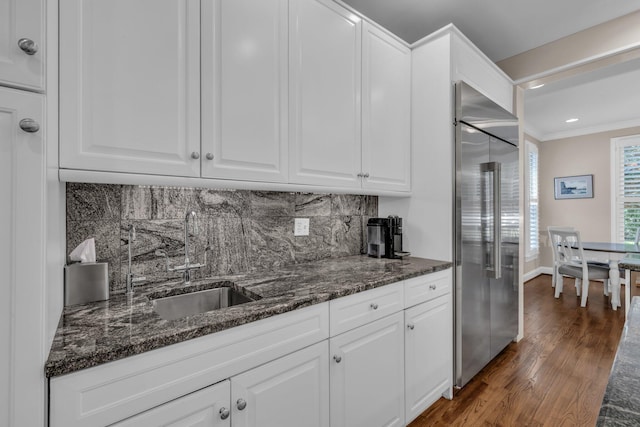 kitchen featuring dark wood finished floors, white cabinetry, built in fridge, crown molding, and decorative backsplash