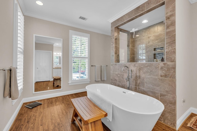 bathroom featuring a soaking tub, baseboards, ornamental molding, and visible vents