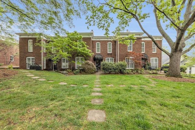 back of property featuring brick siding and a lawn