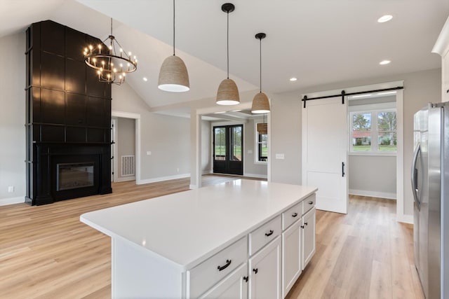 kitchen featuring light wood-type flooring, open floor plan, freestanding refrigerator, white cabinets, and a barn door