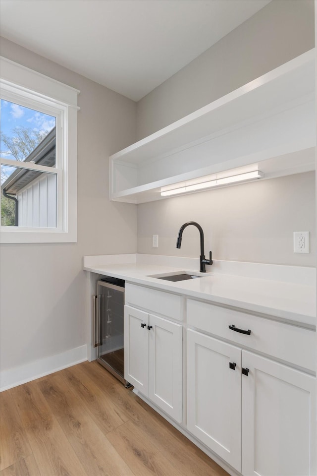 interior space with open shelves, white cabinets, a sink, wine cooler, and light wood finished floors