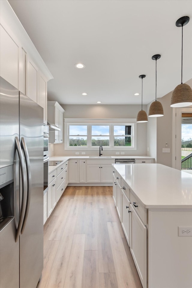 kitchen with light countertops, a wealth of natural light, stainless steel refrigerator with ice dispenser, and black electric stovetop