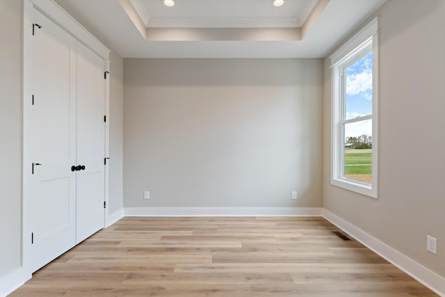 unfurnished bedroom featuring a tray ceiling, recessed lighting, and light wood finished floors