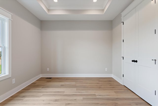 unfurnished bedroom with a tray ceiling, light wood-type flooring, recessed lighting, and baseboards