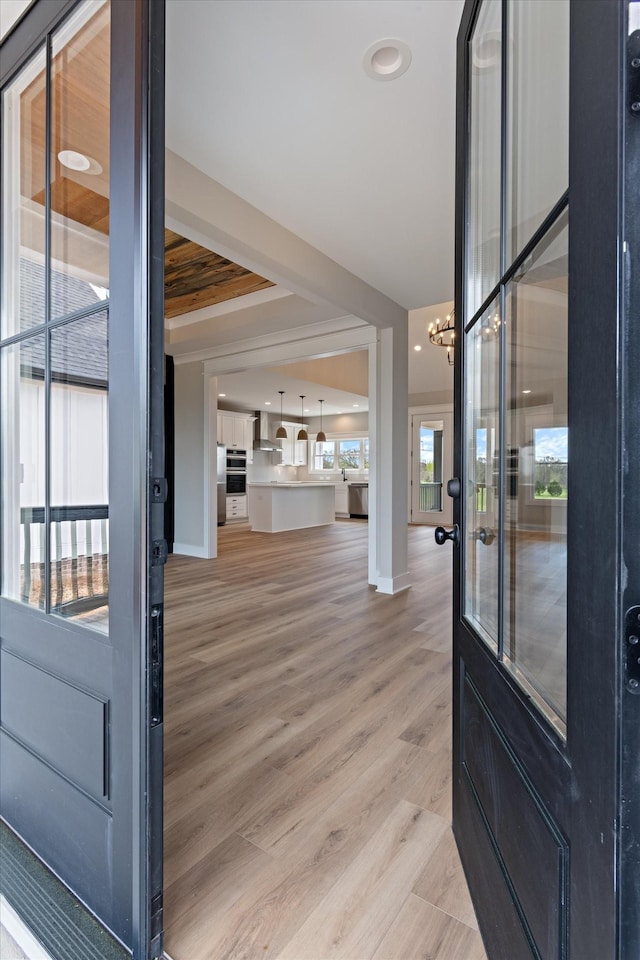 foyer featuring baseboards, a notable chandelier, and light wood-style floors