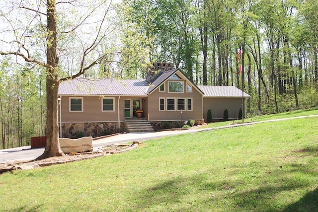 back of house with metal roof and a lawn