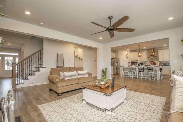 living area featuring ceiling fan, stairway, wood finished floors, and baseboards