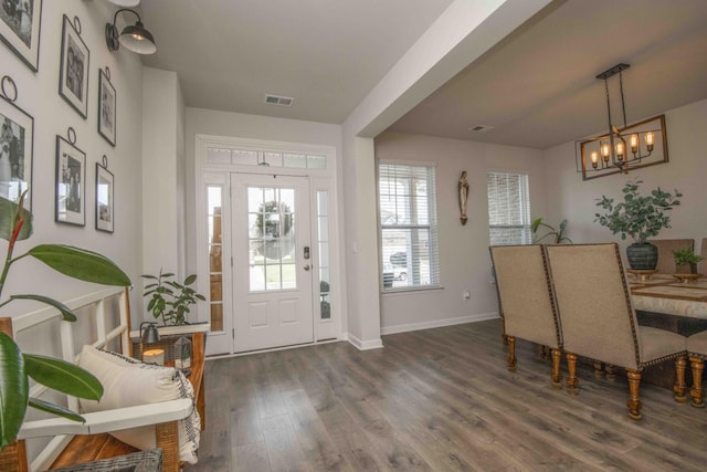 foyer entrance with wood finished floors, an inviting chandelier, baseboards, and visible vents