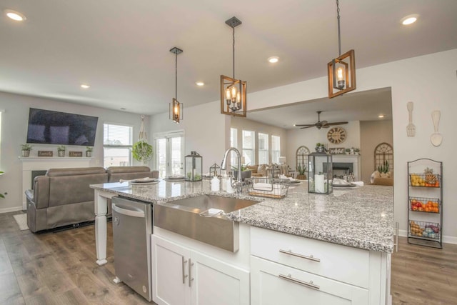 kitchen featuring dishwasher, a sink, open floor plan, a fireplace, and wood finished floors