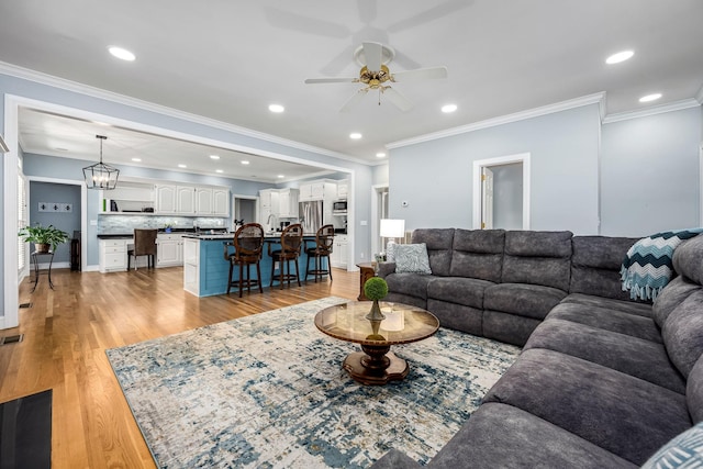 living room featuring light wood-style floors, crown molding, and ceiling fan