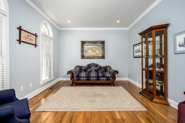 living area with crown molding, baseboards, and wood finished floors