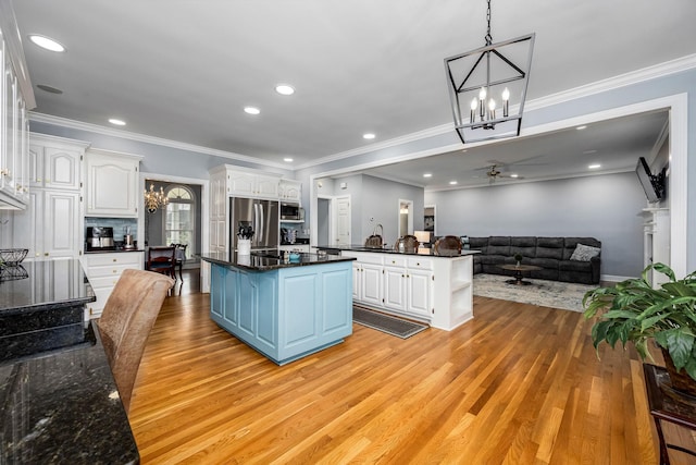 kitchen featuring light wood-style floors, ceiling fan with notable chandelier, white cabinetry, a kitchen island, and appliances with stainless steel finishes
