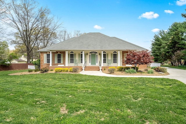 view of front of home with brick siding, a front yard, fence, and covered porch