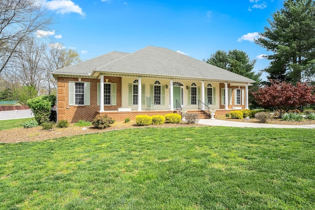 view of front of house with a shingled roof, a porch, brick siding, and a front lawn
