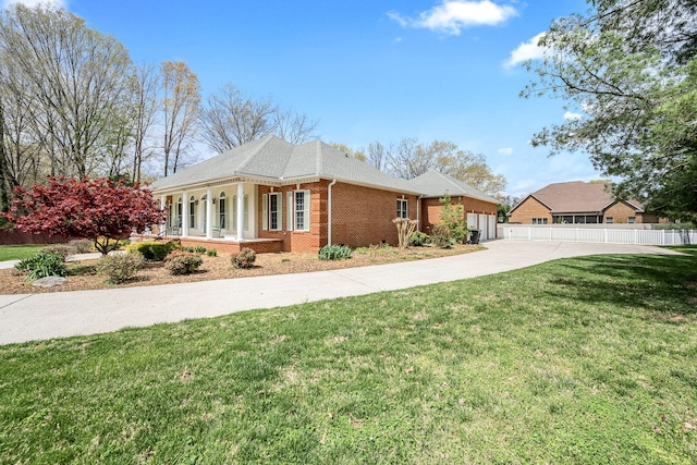 view of side of property with concrete driveway, an attached garage, brick siding, a yard, and fence