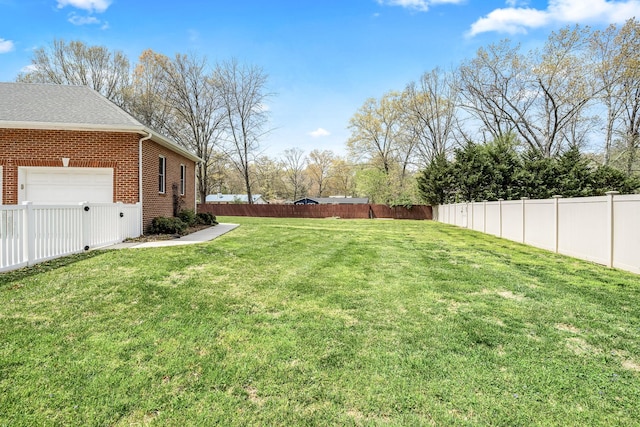 view of yard with a garage and a fenced backyard