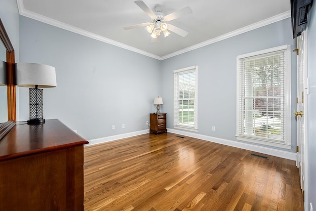 interior space featuring crown molding, wood finished floors, baseboards, and visible vents