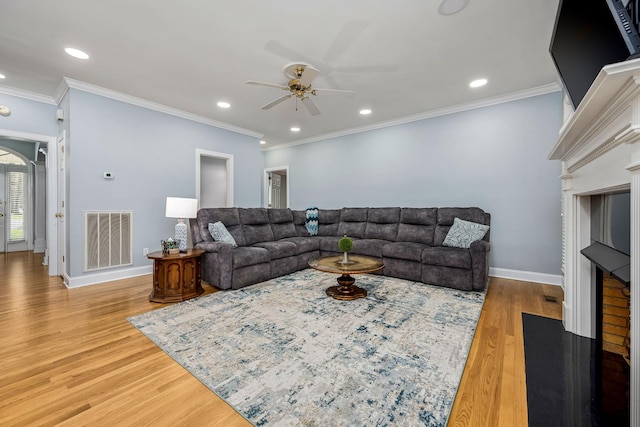 living area with visible vents, baseboards, a ceiling fan, light wood-type flooring, and a fireplace with flush hearth