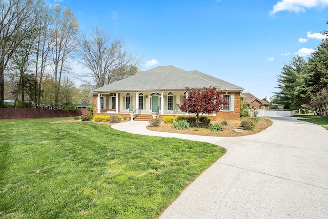 single story home featuring brick siding, a front yard, a porch, and fence