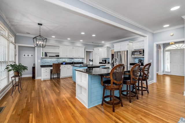 kitchen with white cabinets, open shelves, appliances with stainless steel finishes, a healthy amount of sunlight, and light wood finished floors