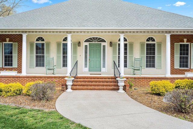 view of front of house featuring stucco siding, a shingled roof, and covered porch
