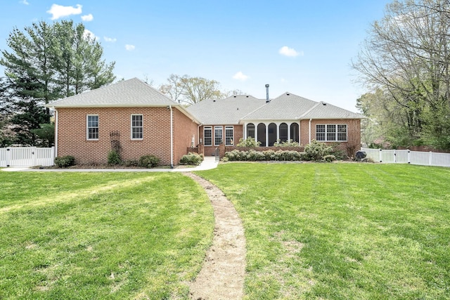 back of property featuring a yard, brick siding, and a gate