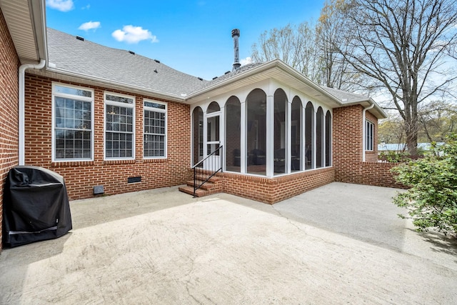 rear view of property with a patio, roof with shingles, crawl space, brick siding, and a sunroom