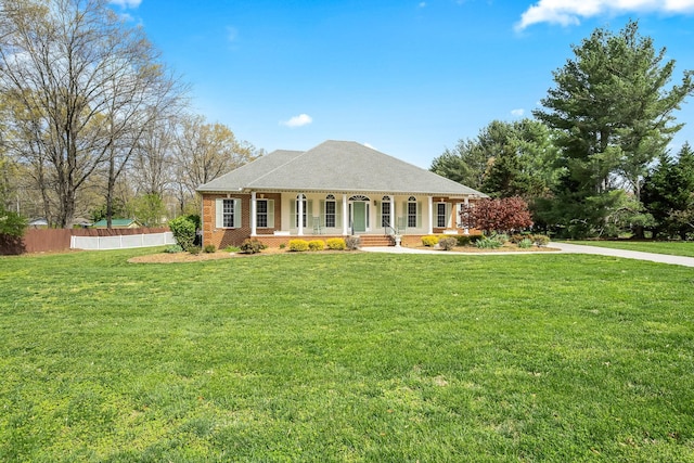 view of front of property with covered porch, a front yard, fence, and brick siding