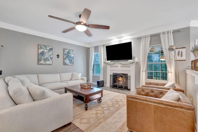living room with ornamental molding, a ceiling fan, wood finished floors, and a fireplace with flush hearth