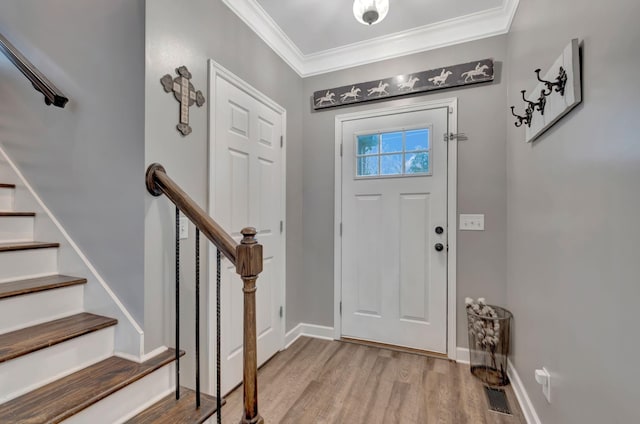 foyer with wood finished floors, baseboards, ornamental molding, and visible vents