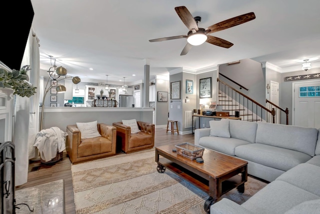 living room with crown molding, wood finished floors, a ceiling fan, and stairway