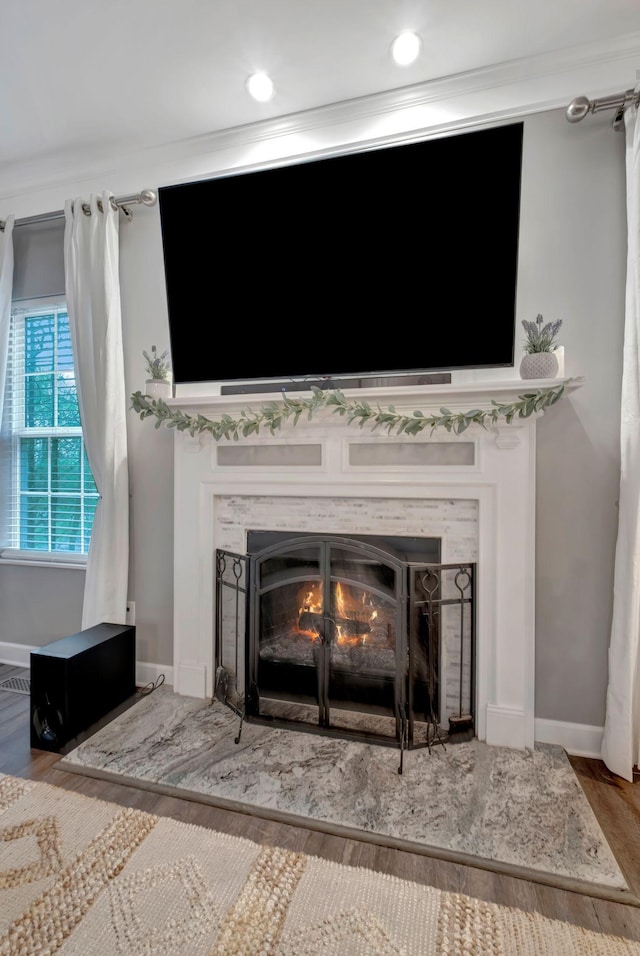 room details featuring a fireplace, baseboards, crown molding, and wood finished floors
