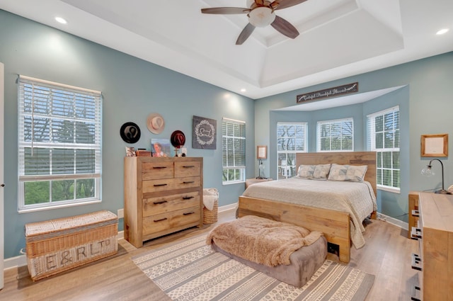 bedroom with multiple windows, recessed lighting, a raised ceiling, and wood finished floors