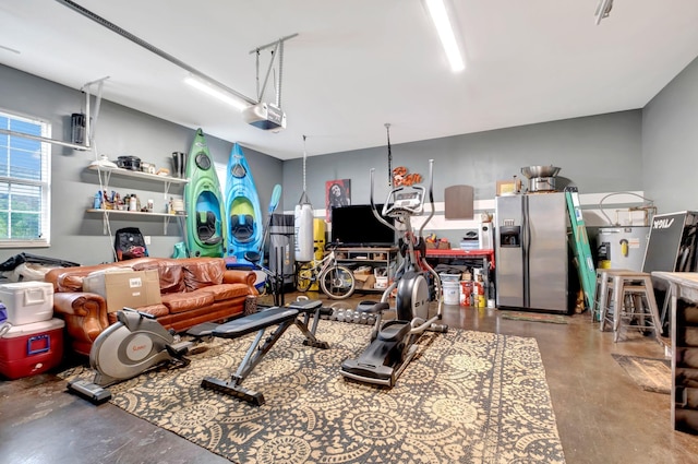 garage featuring a garage door opener and stainless steel refrigerator with ice dispenser