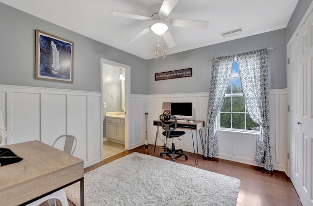 office space featuring a decorative wall, a ceiling fan, and wood finished floors