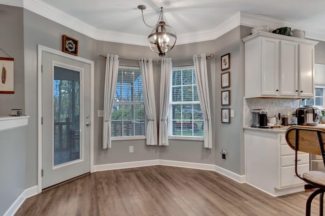 unfurnished dining area featuring plenty of natural light, a notable chandelier, and wood finished floors