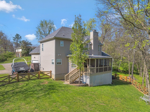 back of property with fence, a yard, a sunroom, and a chimney
