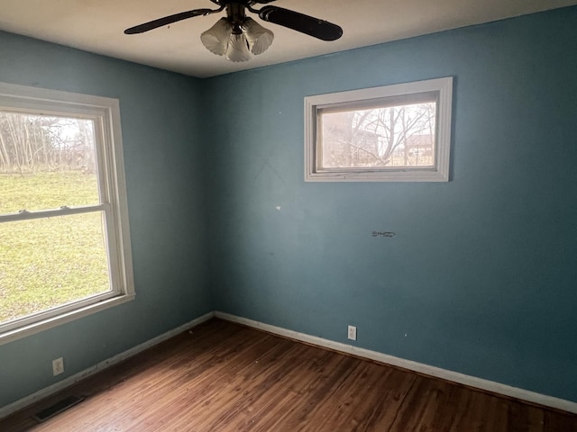 spare room with baseboards, wood finished floors, and a healthy amount of sunlight