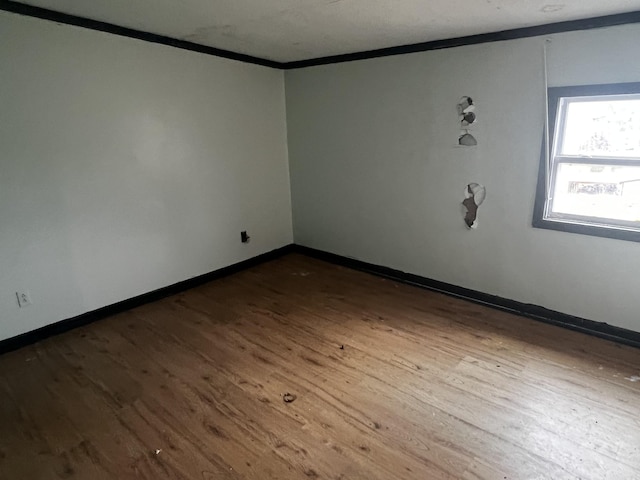 unfurnished room featuring wood finished floors, baseboards, and ornamental molding