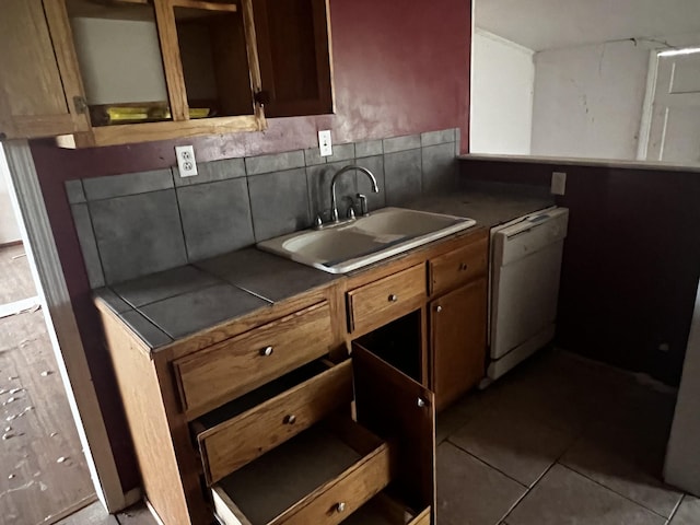 kitchen featuring a sink, dark countertops, tile patterned flooring, and dishwasher