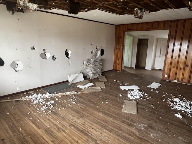 spare room featuring wood-type flooring, baseboards, and wooden walls