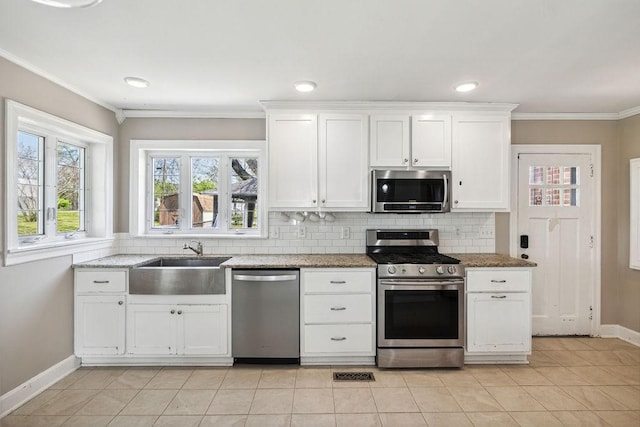 kitchen with baseboards, white cabinets, a sink, appliances with stainless steel finishes, and backsplash