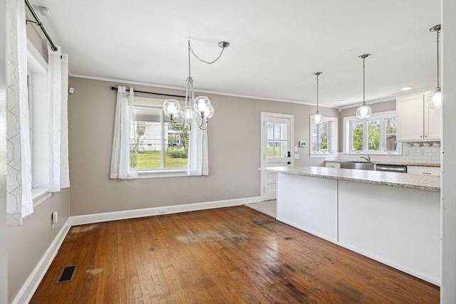 kitchen featuring baseboards, ornamental molding, white cabinetry, visible vents, and hardwood / wood-style flooring