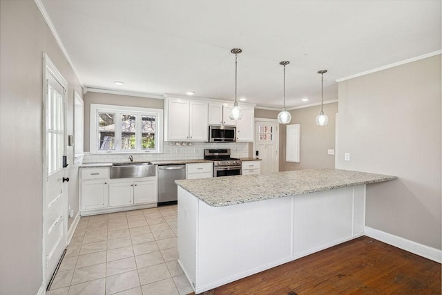 kitchen featuring a sink, appliances with stainless steel finishes, a peninsula, crown molding, and decorative backsplash