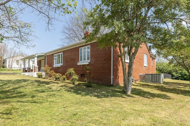 view of property exterior with brick siding, central AC unit, a yard, and a chimney